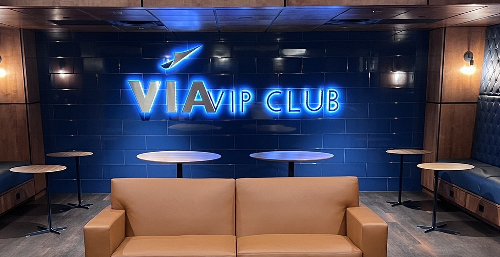 tables, sofa and wall lighting sign inside VIA club
