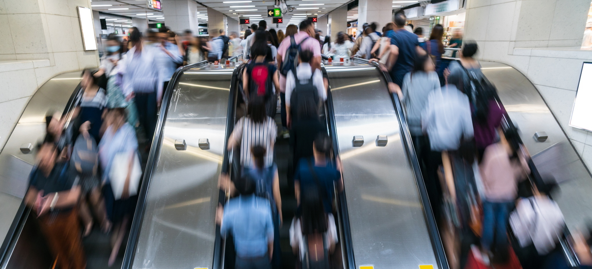 crowded escalators with lots of people (blurred).