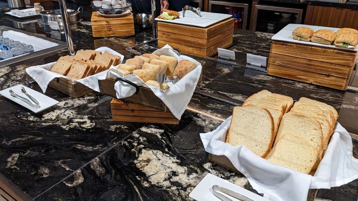 bread, rolls, and sandwiches on buffet.