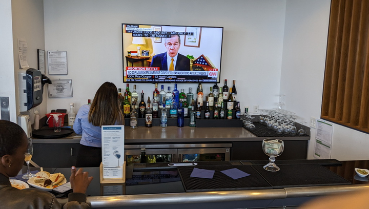bar with alcohol and drinks, television in background.
