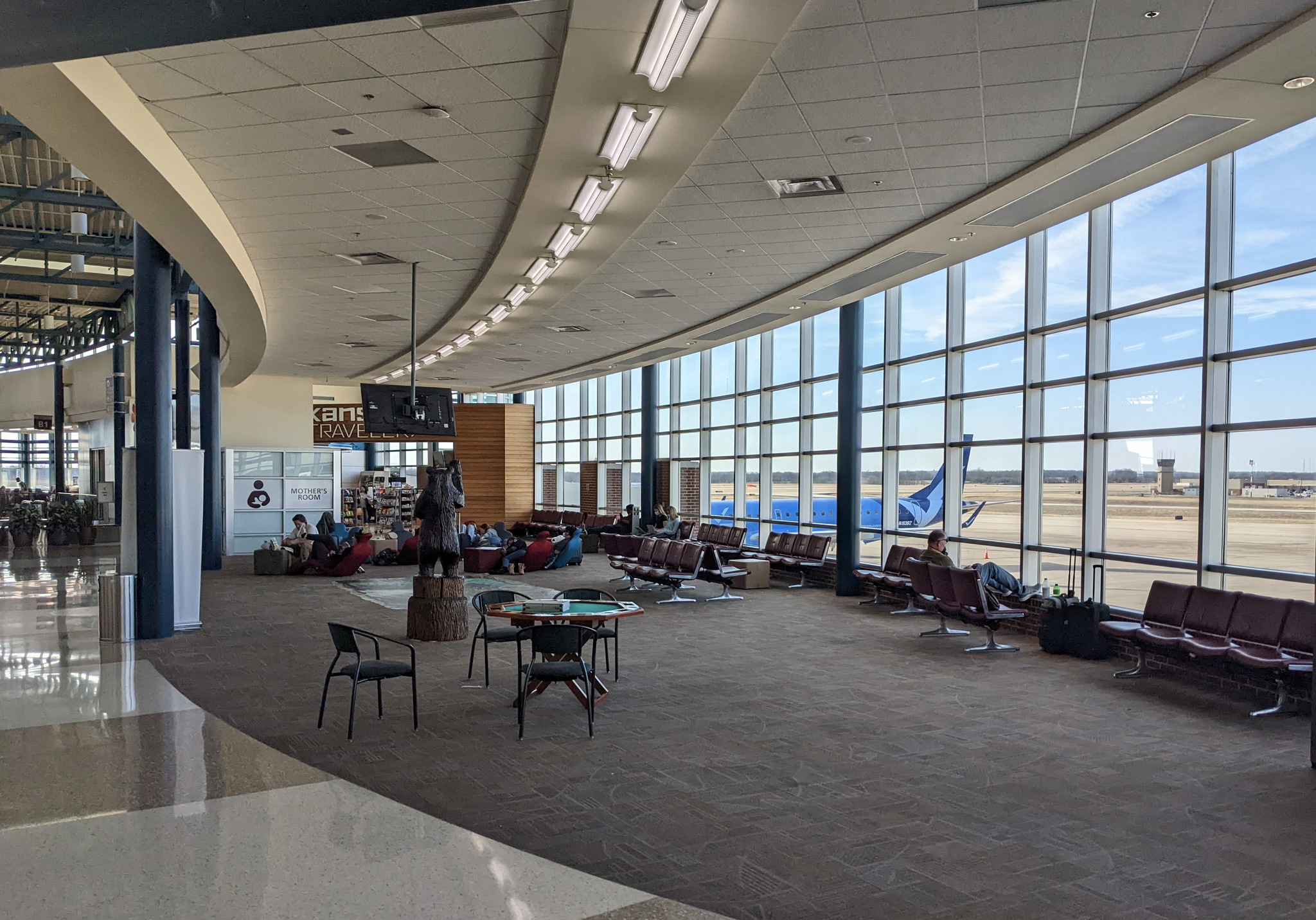 main seating area in XNA airport with chairs and windows.