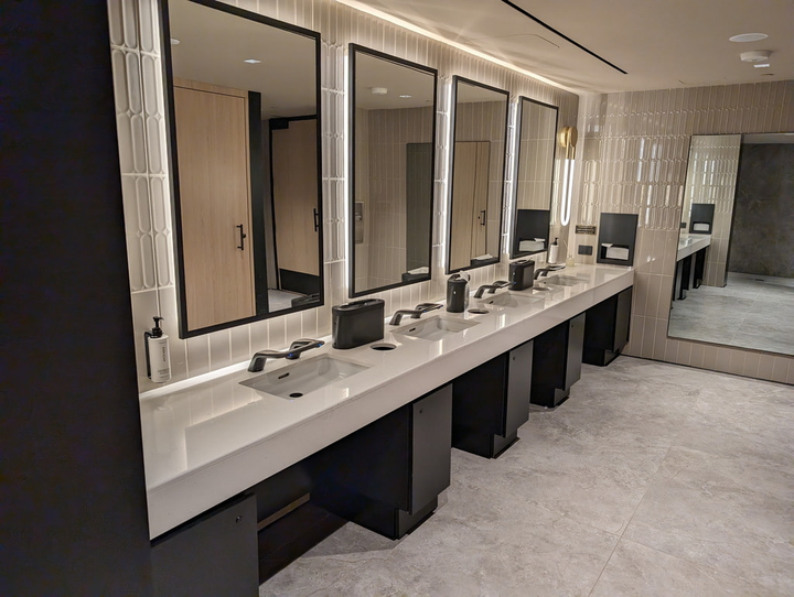 a line of sinks in the restroom with mirror in the background.
