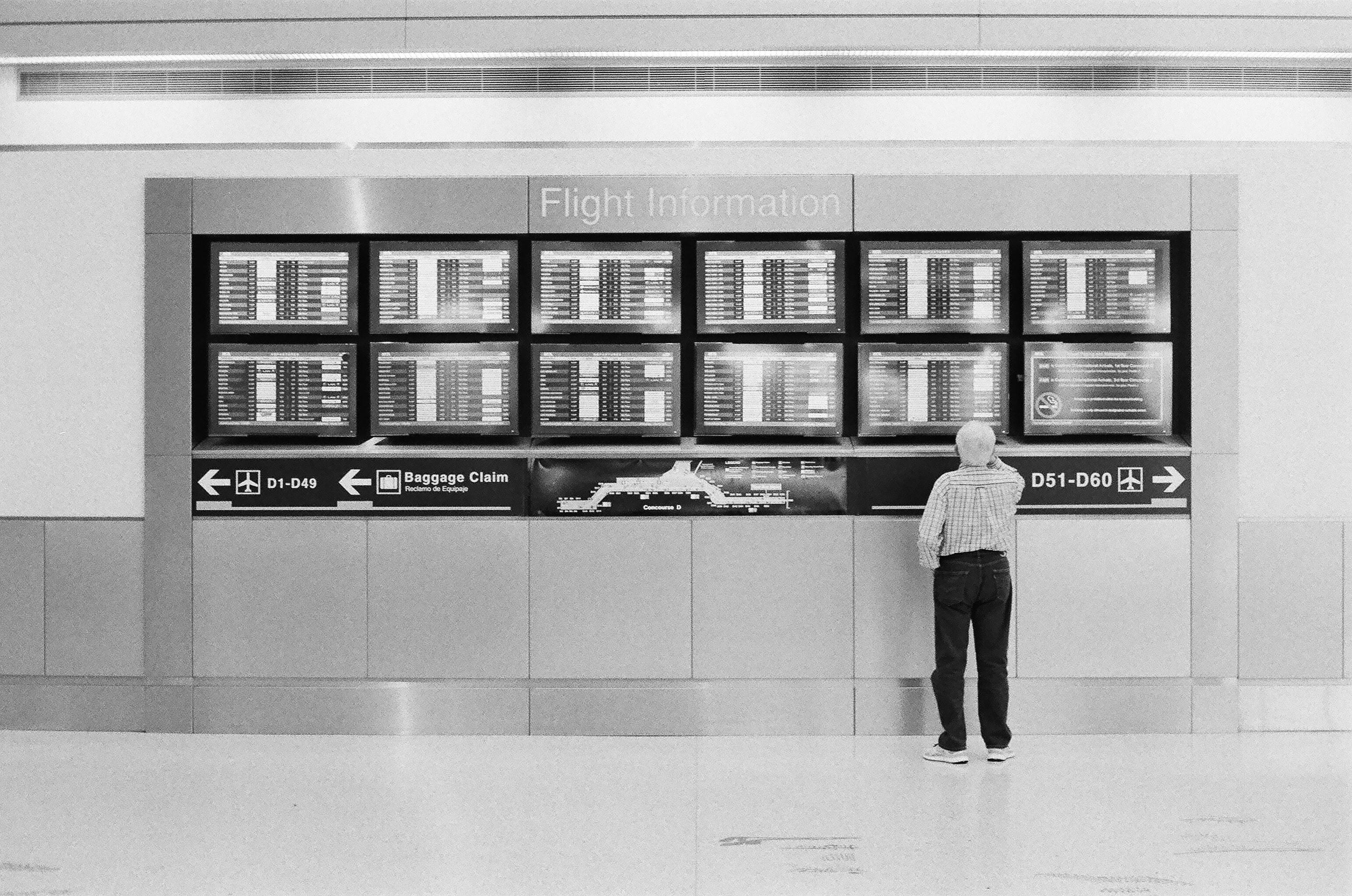 person looking at airport arrival and departure monitors