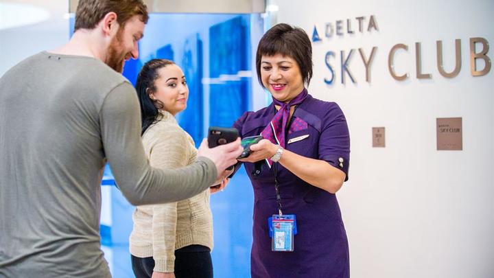 two customers entering delta sky club getting phone scanned.