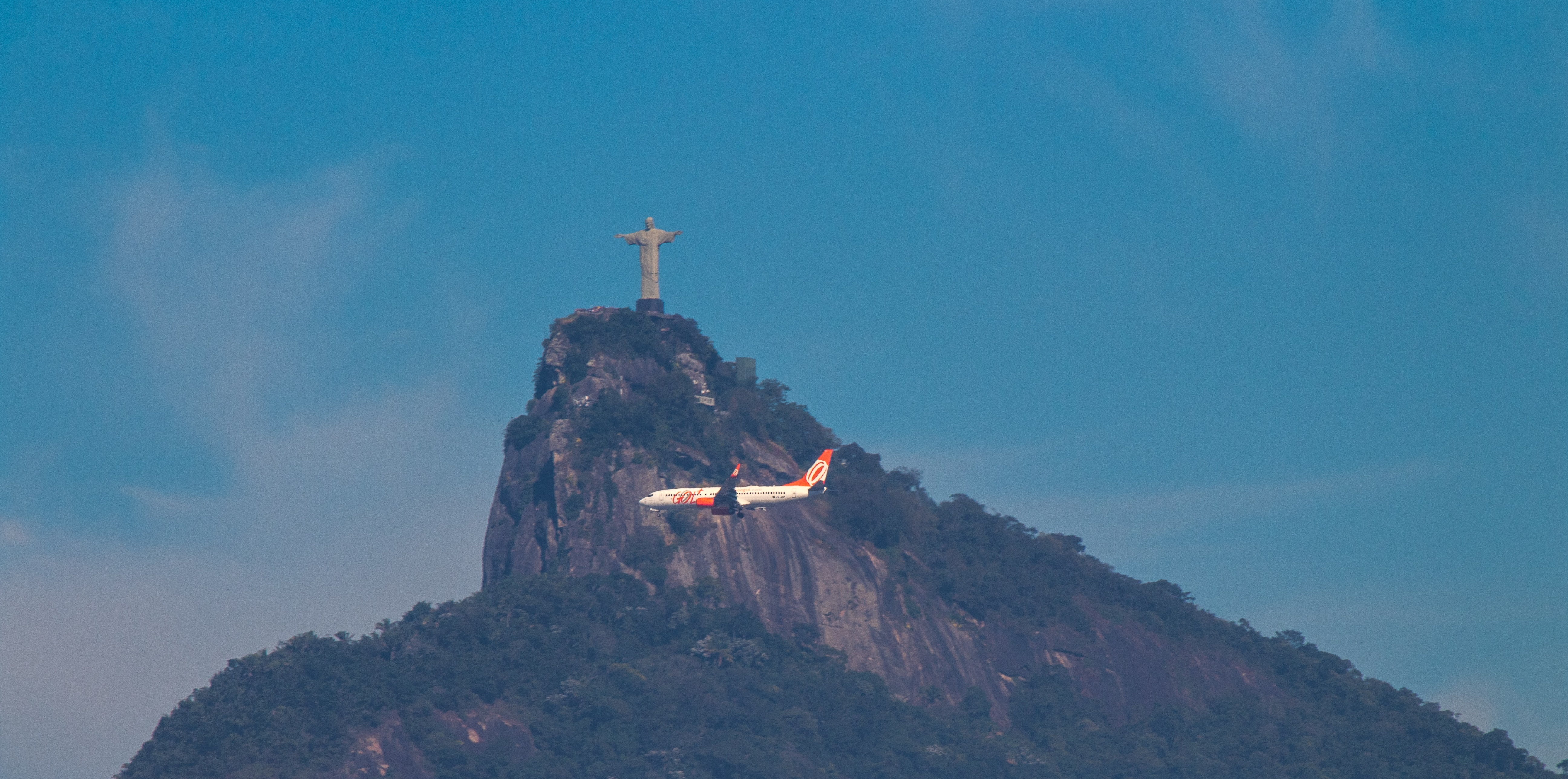 airplane flying in front of Christ the Redeemer 